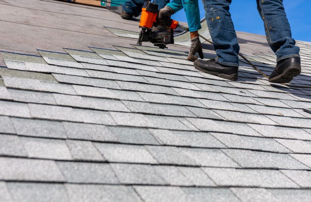 roofer installing asphalt shingles with nail gun, Maple Grove