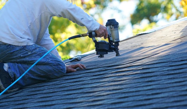 roofer repairing asphalt roof with nail gun, Maple Grove